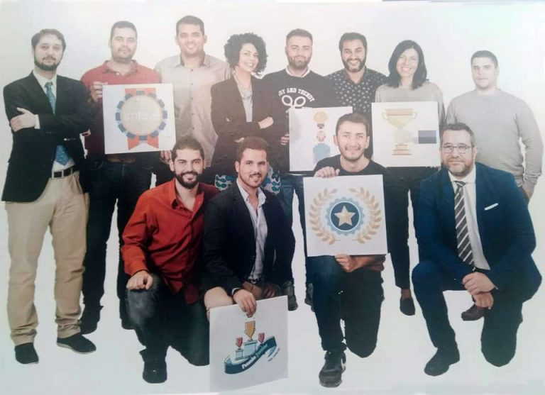 Equipo de Métrica6 con iconos de premios en la exposición de aniversario del Premio Junior Empresas 2017 donde la empresa forma parte de la historia del certamen